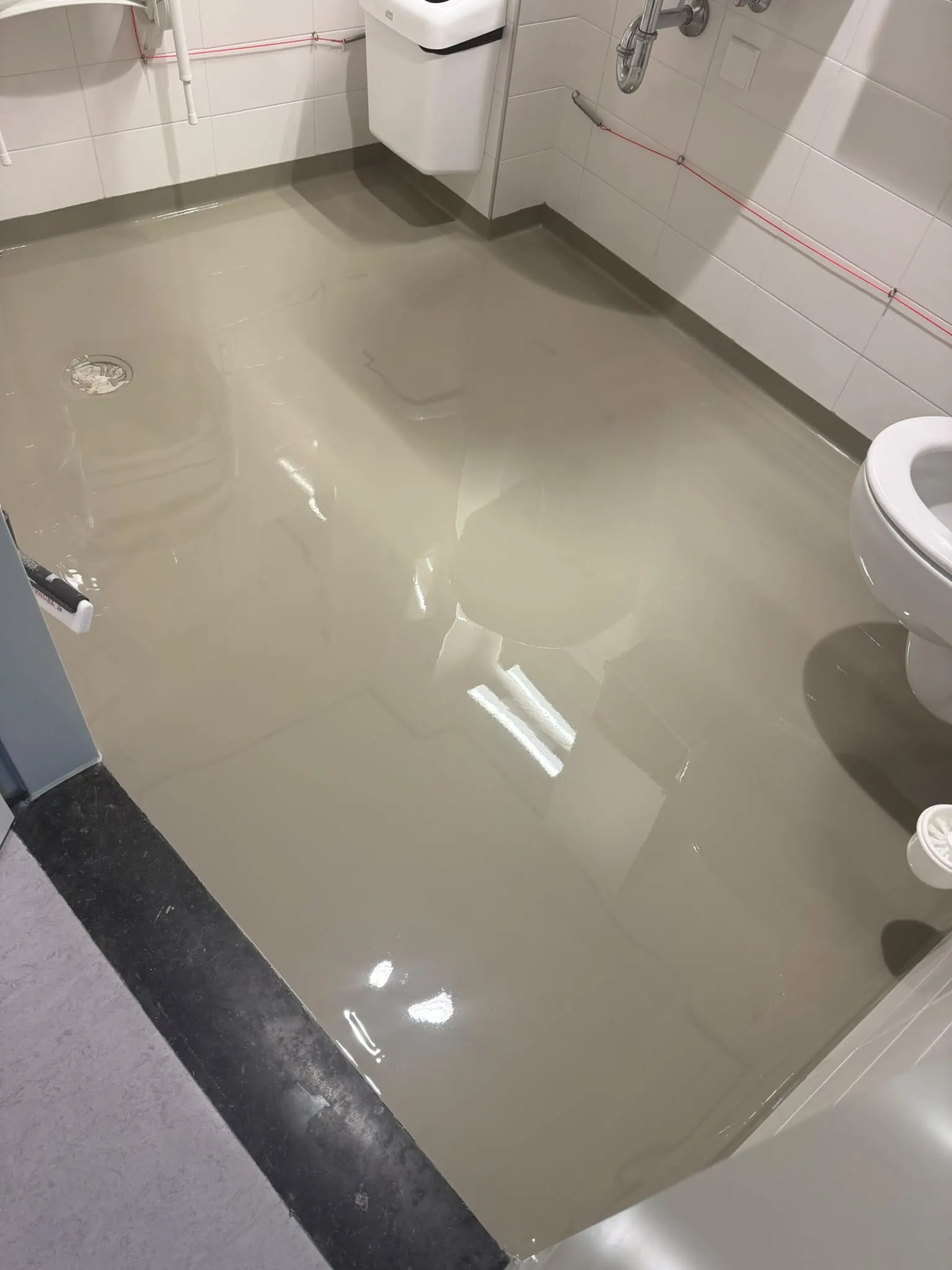 Sanitaire ruimte met een glanzende, grijsbeige gietvloer