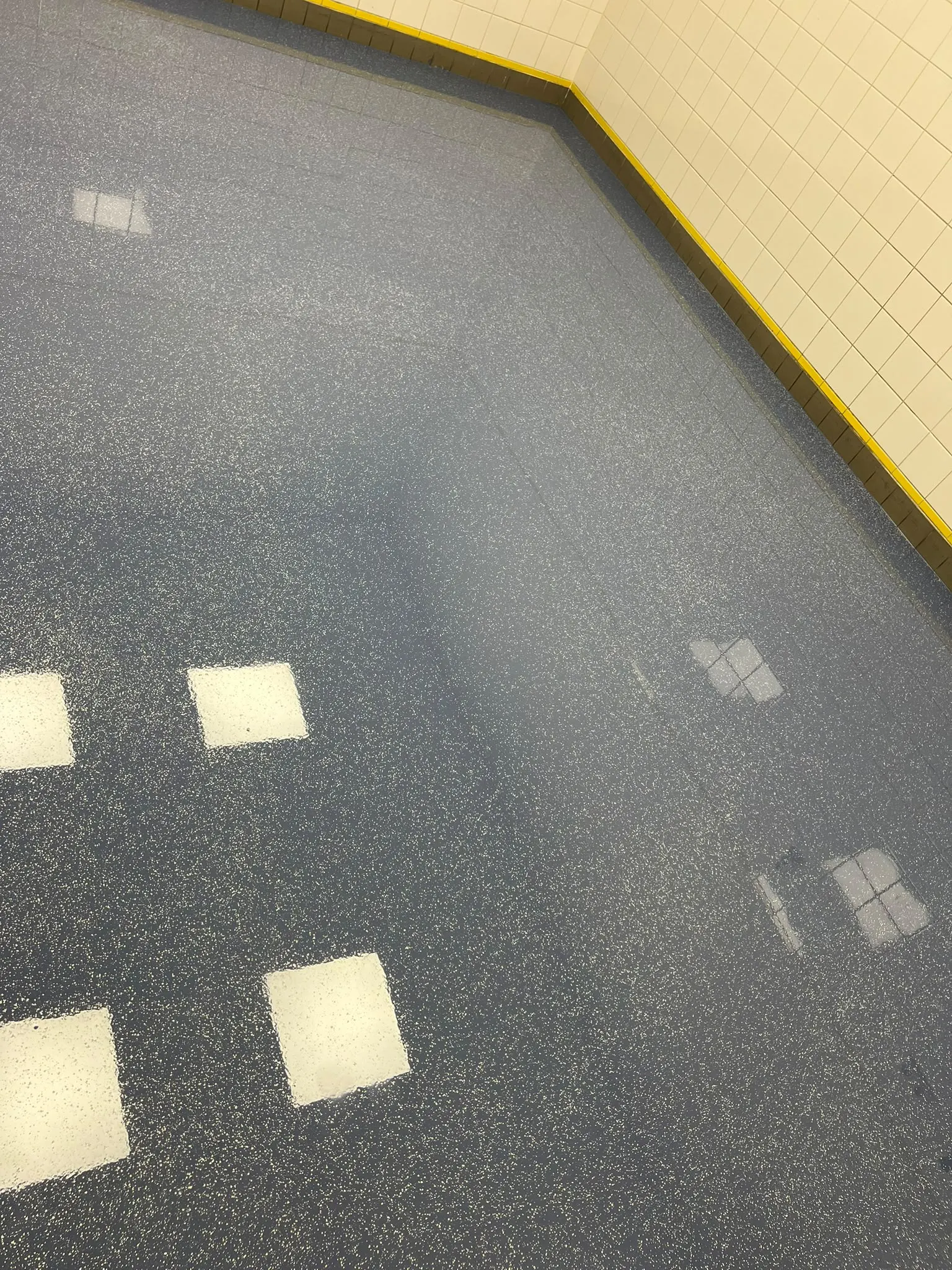 Blauwgrijze gietvloer met vlokken in een ruimte met witte tegels